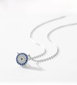 Macro shot of silver Evil Eye pendant with blue and white crystals on thin chain