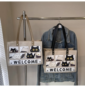 Detail of canvas tote bags with black and white cartoon cat print and colorful handles