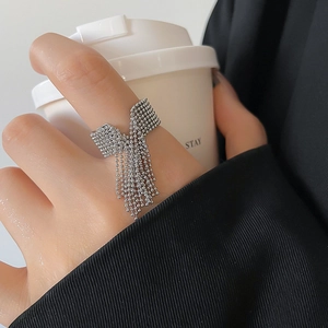Detail of silver beaded tassel ring on hand, featuring flowing metallic chain design