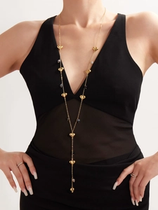Detailed view of a gold Y-shaped necklace with hollow hearts and agate beads on a model