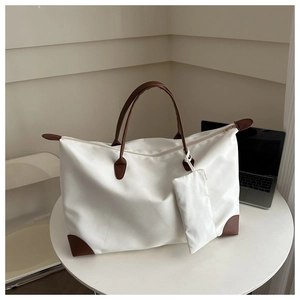 Detail of waterproof nylon tote bag showing leather corner trim and matching small pouch