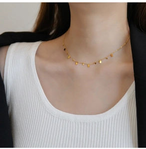 Close-up of gold minimalist necklace with multiple small rectangular pendants on model