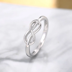 Macro-opname van een gepolijste zilveren infinity ring op wit marmeren blad