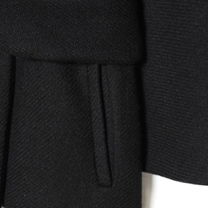 Close-up of black houndstooth wool jacket texture and detailed pocket stitching