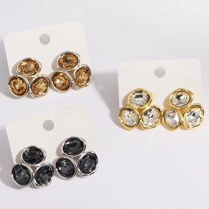 Dettaglio di orecchini geometrici in zircone nei colori oro, argento, ambra e nero