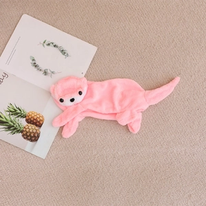 Pink plush otter animal toy accessory on soft beige background with decorative magazine
