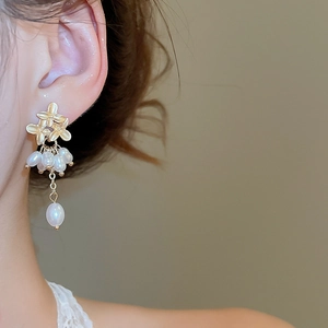 Detail of vintage gold flower earrings with elegant pearl tassels worn by a model