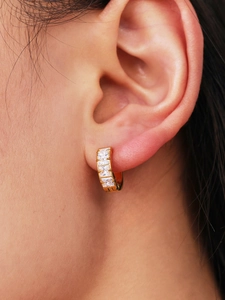 Detail of gold-plated hoop earring with four princess-cut cubic zirconia stones on the model