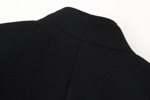 Détail du tissu en laine noire montrant la texture et les coutures de l'épaule