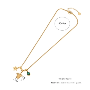 Detail view of gold necklace with star, turtle pendants and green stone with specifications