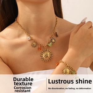 Detail showing bohemian gold-plated necklace and bracelet set with sun and heart charms