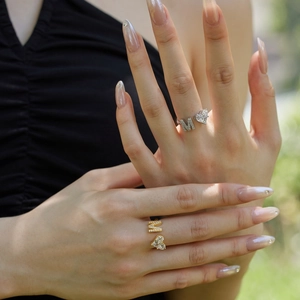 Detail of S925 silver and gold heart rings with letter M and zircon stone on hands