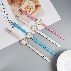 Detail view of four minimalist women's quartz watches with pastel leather bands on a magazine