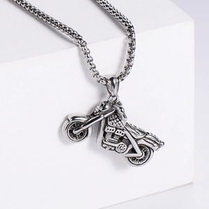 Detailed studio shot of a polished silver motorcycle pendant necklace on a white base