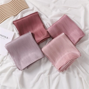 Detailed view of layered satin fabric samples in pink and purple shades with silk texture