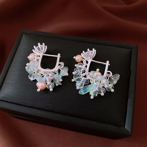 Close-up of silver earrings featuring pink pearls, aquamarine stones, and crystal tassels