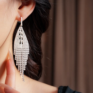 Close-up of model wearing silver tassel earrings with sparkling rhinestones and long fringe