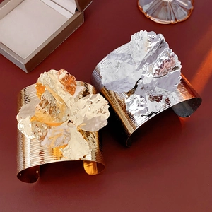 Close-up of gold and silver metallic wide bangles with textured hammered floral patterns