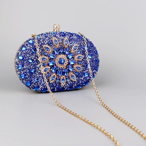 Detailed macro view of the dark blue rhinestone flower and gold metal frame on the clutch