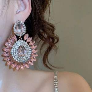 Close-up of luxury pink pear-cut crystal earrings with sparkling diamond halo