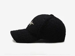 Detail view of black faux lambswool baseball cap featuring artistic letter embroidery