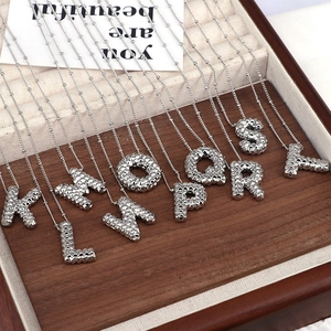 Detailed top view of silver alphabet pendant necklaces arranged in a wooden jewelry box