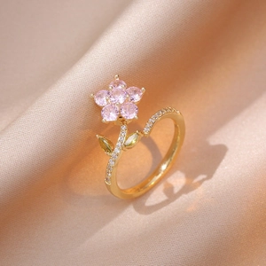 Macro shot of gold flower ring with pink petals and yellow gems on silk fabric