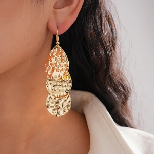 Détail de boucles d'oreilles dorées à texture martelée portées par un mannequin