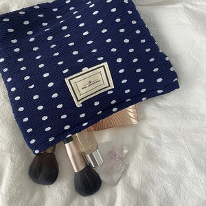 Detail of navy blue polka dot makeup bag with crinkle texture and Pleasant Time label