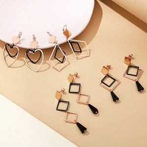 Détail des boucles d'oreilles géométriques en titane rose doré avec pendentifs noirs