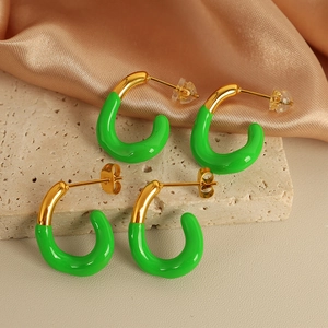 Minimalistische goldene C-Creolen mit grüner Emaille auf hellem Steinhintergrund