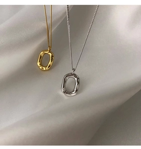 Macro shot of lava textured oval doughnut pendants in gold and silver on white silk