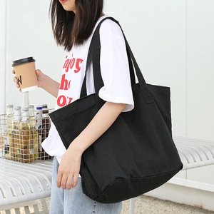 Minimalist black canvas tote bag for women showing a large capacity shoulder carry style
