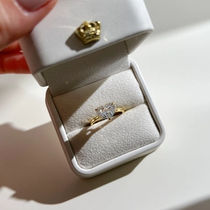 Detailed macro view of a heart-cut cubic zirconia gold ring in a luxury white gift box