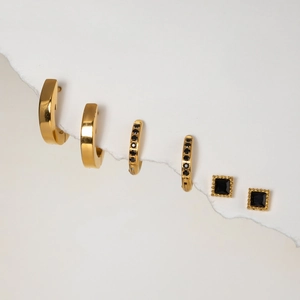 Detail of gold stainless steel hoop earring set featuring elegant black gemstone accents