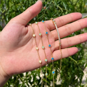 Detail of four gold S925 silver bracelets with opal and zircon stones on a wrist