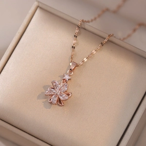 Rose gold flower and star pendant necklace with cubic zirconia on beige jewelry box