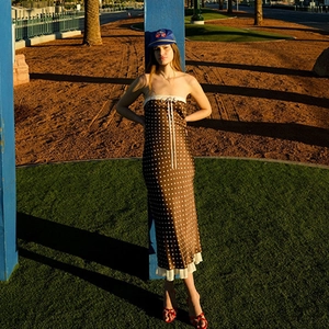 Detail of a brown polka dot satin dress with delicate white lace trim in an outdoor park setting