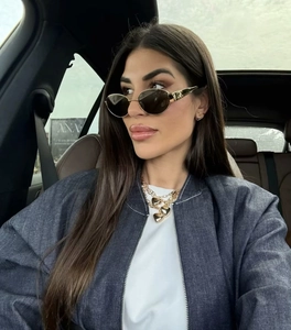 Detail of trendy gold sunglasses and layered heart necklace on model in car