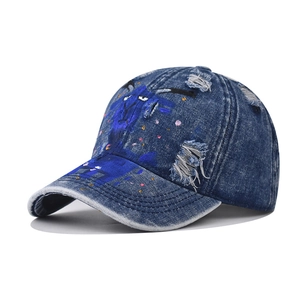 Detailed view of distressed denim baseball cap with creative hand-painted graffiti