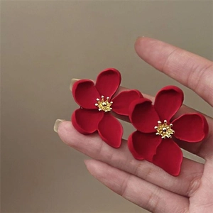 Detail of red floral earrings featuring matte petals and golden center studs
