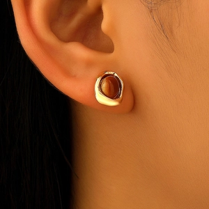 Nahaufnahme von Vintage-Tigerauge-Ohrringen mit goldenem Finish am Ohr des Models