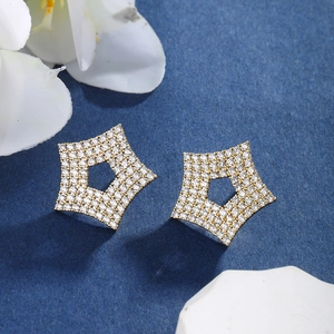 Macro shot of gold star-shaped earrings with clear cubic zirconia on blue background