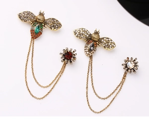Detailed close-up of retro bee brooches with gemstone inlay and layered metal chains