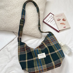 Detailed view of British plaid pattern and textile label on green crossbody bag
