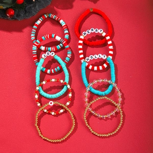 Close-up of Christmas beaded bracelets with JOY and MERRY letters on red background