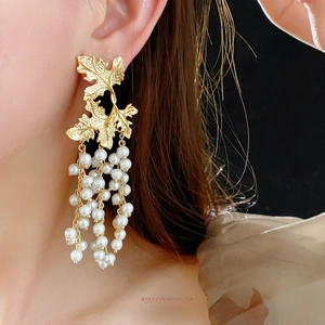 French vintage gold maple leaf earrings with white pearl tassels worn by a model