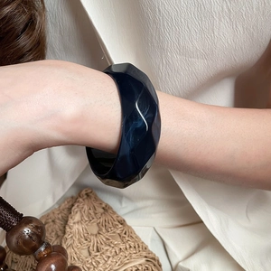 Close-up of a wide geometric acrylic leopard print bangle worn by a model in nature style