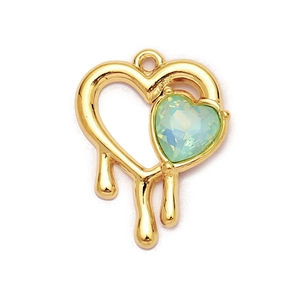 Macro shot of 18K gold heart pendant with green gemstone and melting fluid design