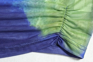 Detail of blue and green mesh fabric showing ruched texture and double-stitch hem